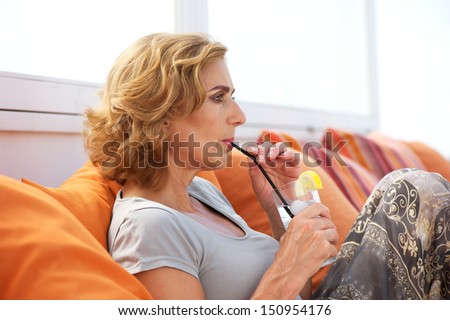 Profile portrait of an older woman drinking water out of glass at restaurant