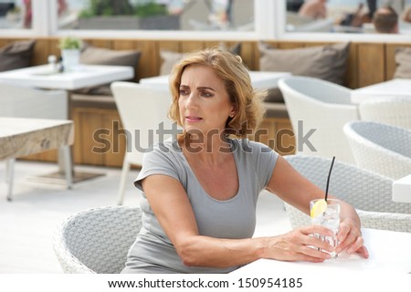 Portrait of a mature woman sitting alone with a glass of water at restaurant