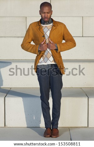 Full length portrait of an attractive male fashion model holding jacket outdoors