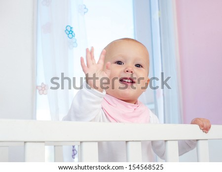 Closeup portrait of a cute baby waving hello with hand