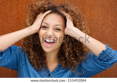 Closeup portrait of an attractive young woman laughing with hands in hair