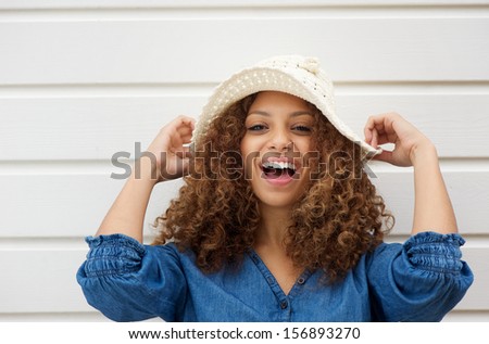 Closeup portrait of a cheerful young woman with hat laughing outdoors