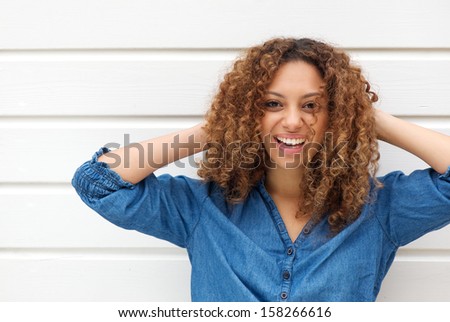 Closeup portrait of a happy young woman smiling with hands in hair