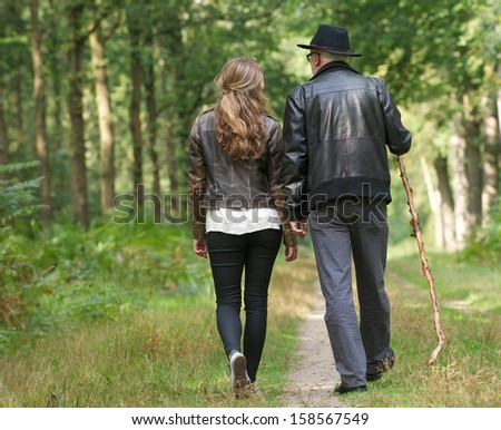 Portrait of a father and daughter walking on path in the woods - from behind
