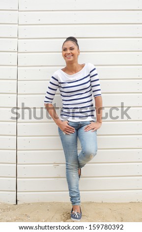 Full length portrait of a happy young woman standing outdoors and laughing