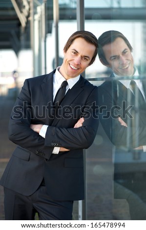 Portrait of a happy businessman relaxing outdoors and smiling with arms crossed