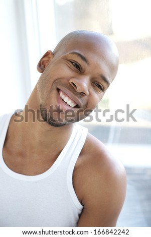 Close up portrait of a happy young man smiling and looking out of window