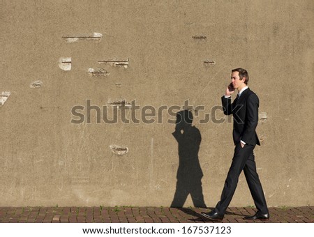 Full body portrait of a business man walking and talking on cellphone