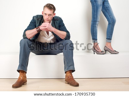 Portrait of an attractive male model sitting with a pair of female legs on the side
