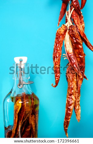 Hanging red chili peppers set out to dry with jar of preserved chili peppers