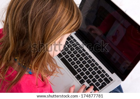 Close up portrait of a young girl looking at laptop screen - from behind