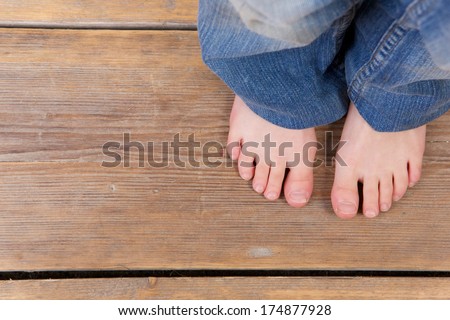 Close up barefoot girl standing on wooden floor - from above