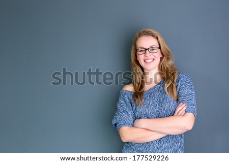 Close up portrait of a business woman standing against gray background with arms crossed