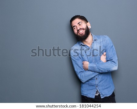 Close up portrait of a stylish young man with beard smiling with arms crossed