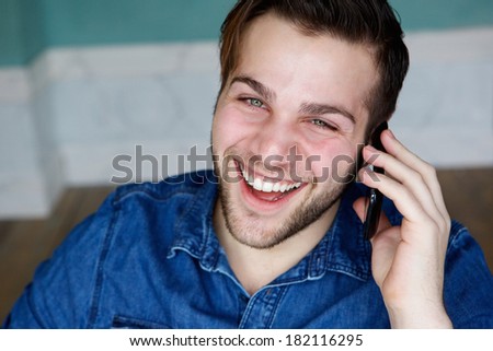 Close up portrait of a young man smiling and calling on mobile phone