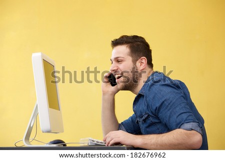 Close up portrait of a happy business man talking on phone and looking at computer screen at the office