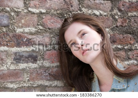 Close up portrait of a female fashion model posing against brick wall outdoors