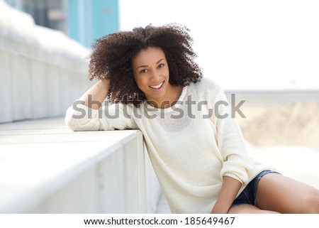 Close up portrait of a beautiful black woman relaxing outdoors. Smiling face of friendly young female fashion model