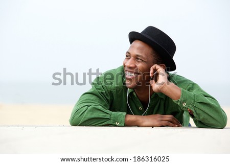 Close up portrait of a young man smiling and listing to music outdoors