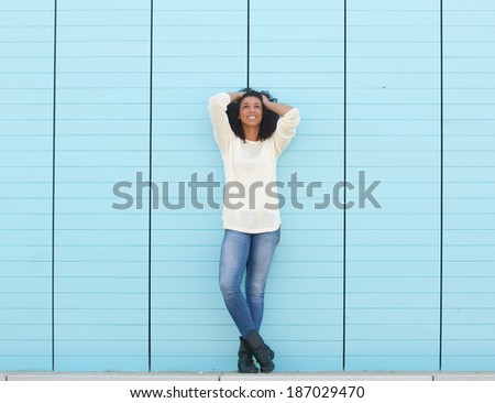 Full length portrait of a beautiful young woman standing outdoors with hands in hair