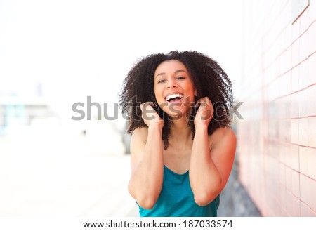 Close up portrait of a cheerful young black woman laughing outdoors