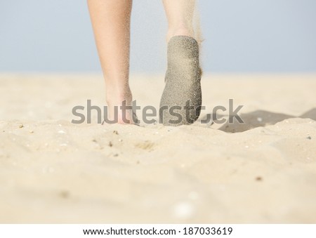 Low angle from behind view of woman walking with flip flops on beach
