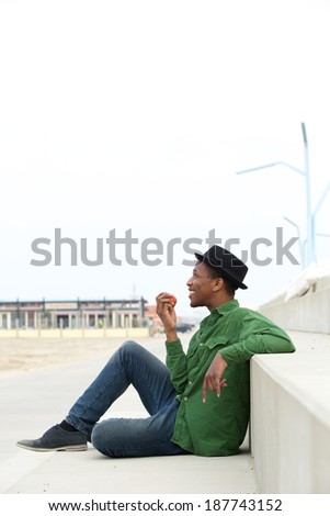 Portrait of a healthy young black man eating apple outdoors