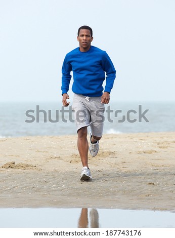 Handsome young african american man jogging at beach. Healthy lifestyle