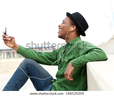 Portrait of a smiling young man listening to music on cellphone