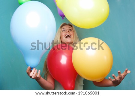 Portrait of a cheerful young blond woman playing with balloons