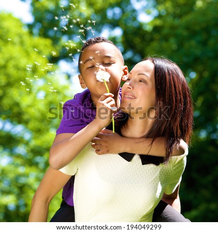 Close up portrait of a happy single mother with son blowing dandelion