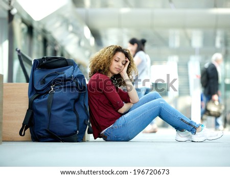 Tired young woman sleeping at airport with luggage