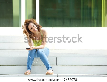Portrait of a young woman sitting outside with earphones