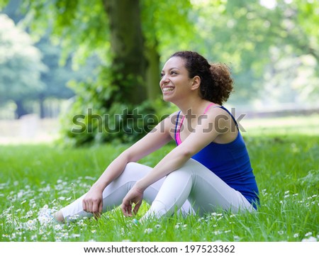 Young woman resting on grass in the park after workout