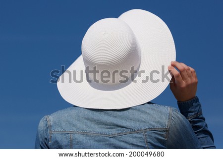 Close up portrait of the back of a young woman with white sun hat from behind
