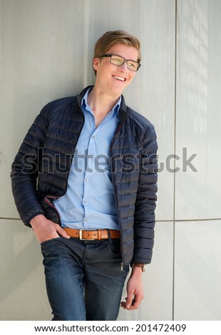 Portrait of a trendy young man with glasses smiling outdoors