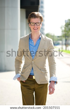 Portrait of a smiling young man with glasses walking outside