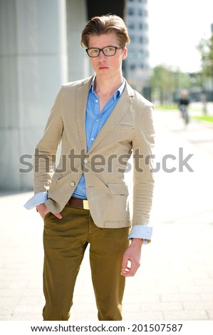 Portrait of a handsome young man with glasses standing outdoors