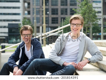 Portrait of male twins with glasses smiling outdoors
