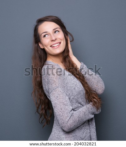 Profile portrait of an attractive young woman smiling with hand in hair