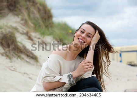 Portrait of a young woman smiling outdoors with hand in hair