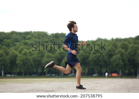 Full body side view of an athletic young man running outdoors