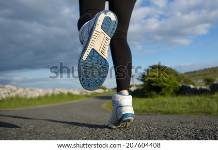 Low angle close up woman running in sneakers on road