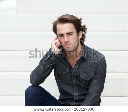 Close up portrait of a cool guy sitting outside with mobile phone