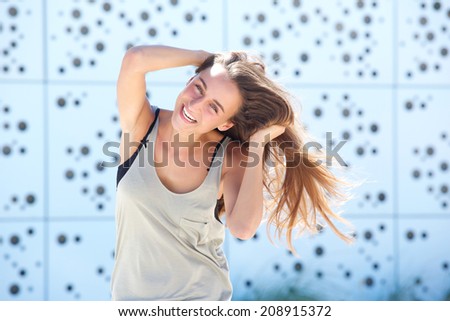 Portrait of a joyful young woman laughing with hand in hair