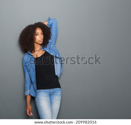 Portrait of a black female fashion model posing with hand in hair on gray background