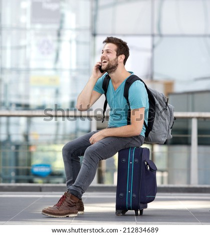 Portrait of a young man relaxing at airport and talking on mobile phone