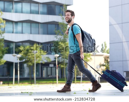Portrait of a smiling young man traveling with suitcase and bag