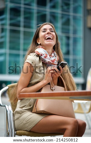 Portrait of a young woman laughing at text message on mobile phone