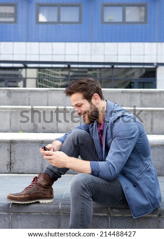 Portrait of a smiling young man text messaging on mobile phone